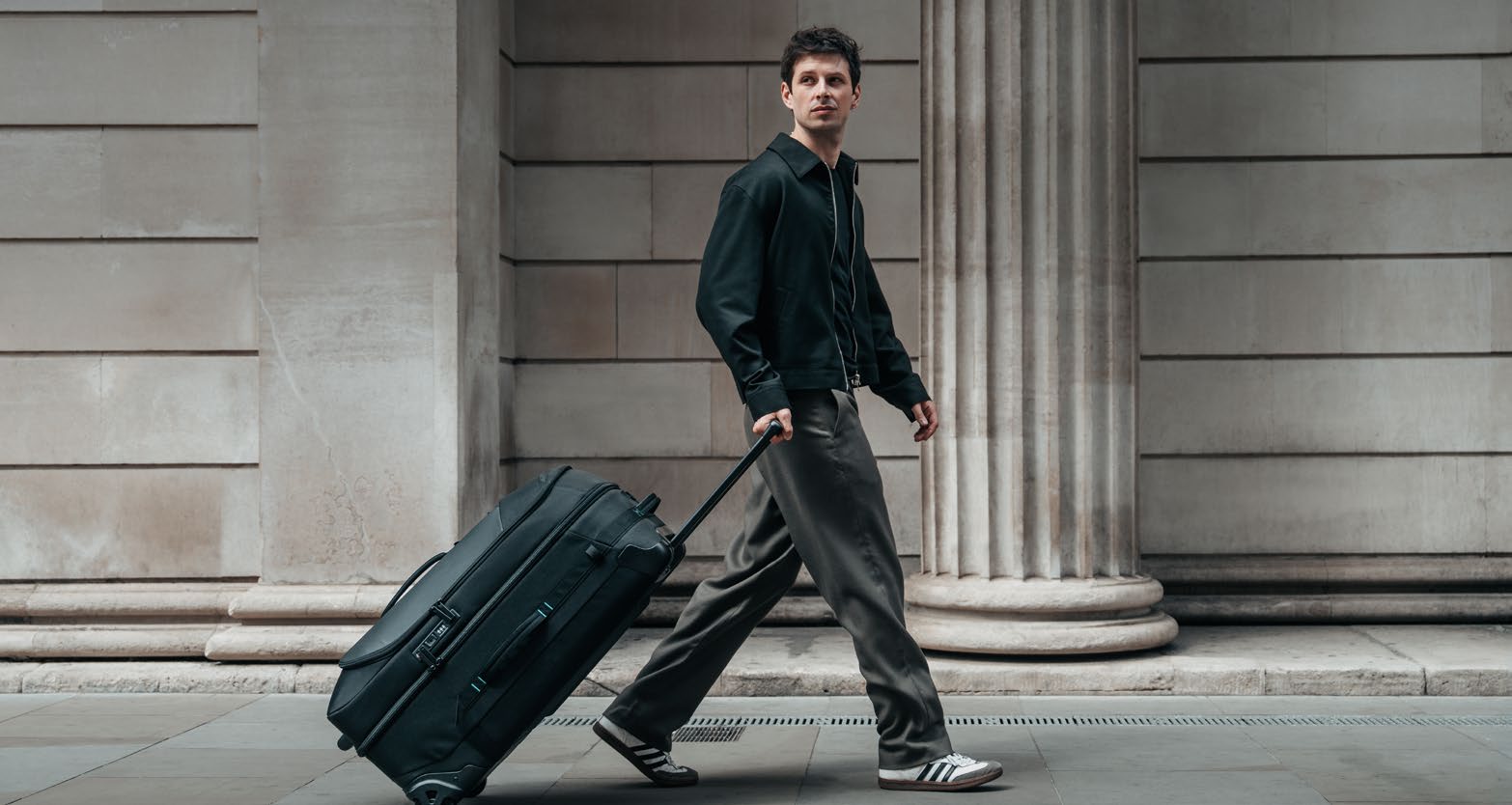Man pulling the luggage through a city street